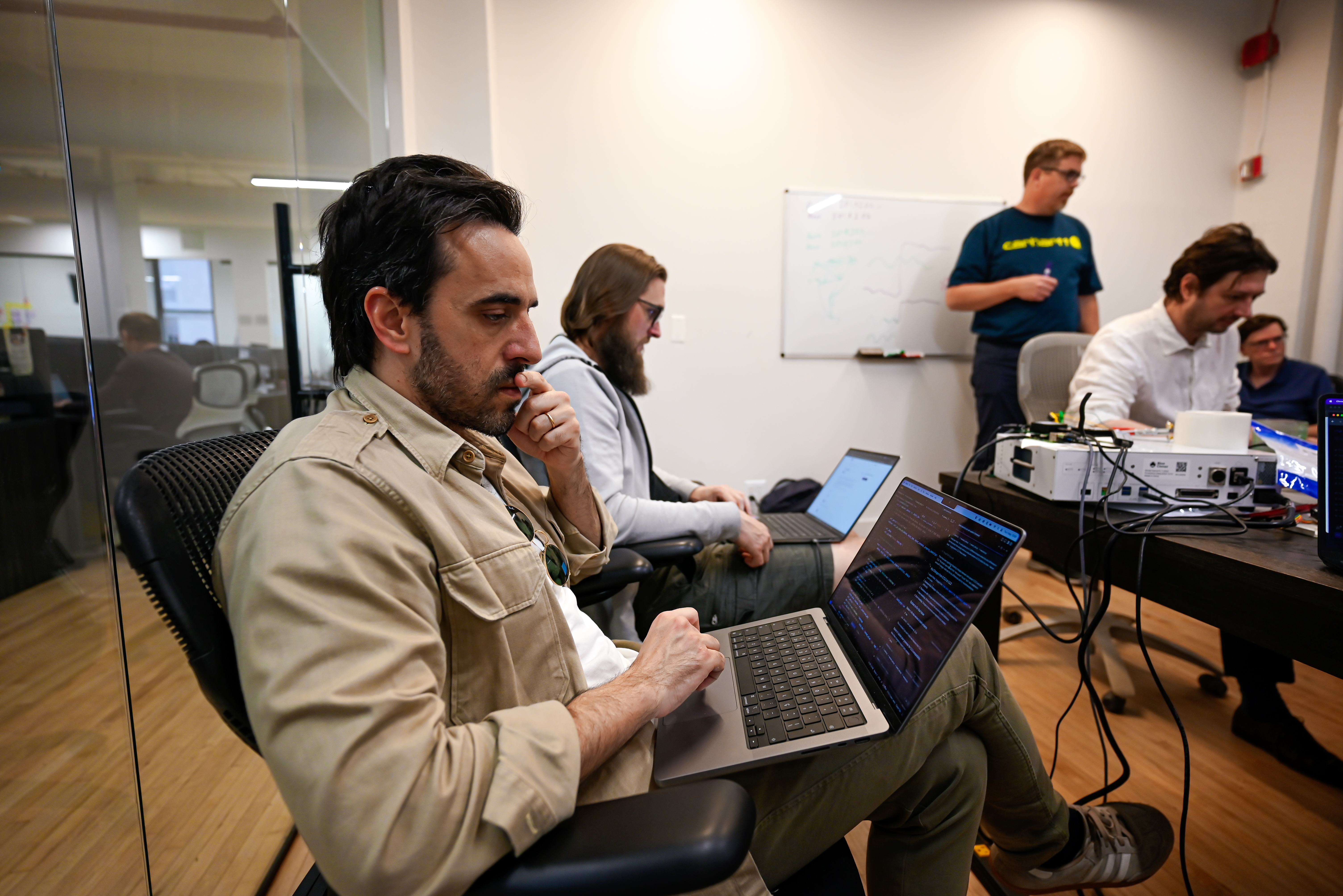 Engineers coding with whiteboard in background
